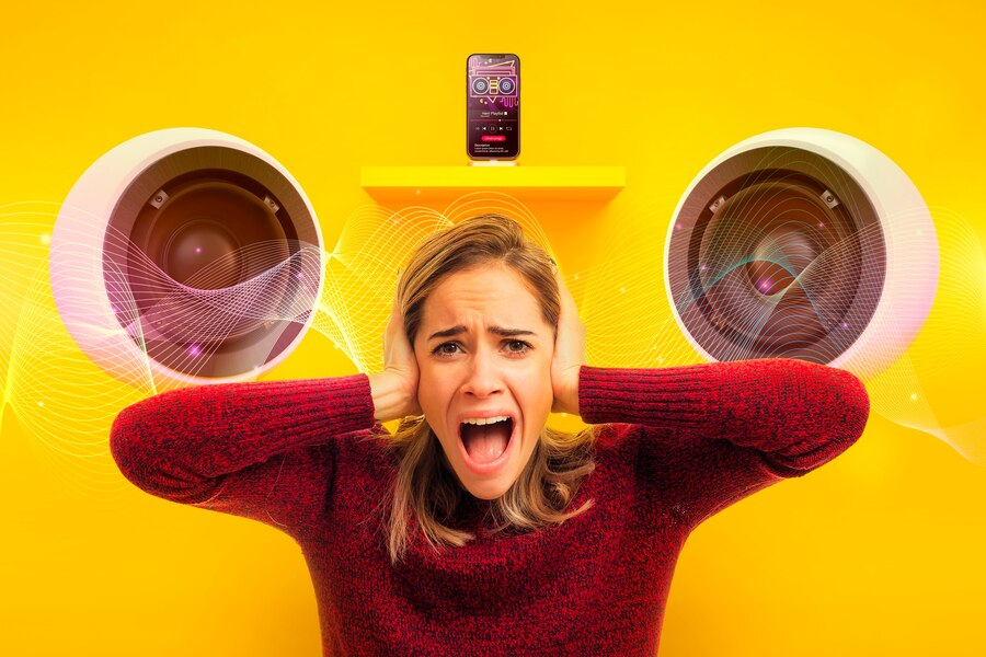 Imagem conceitual sobre o excesso de ruído digital. Uma mulher de suéter vermelho grita com as mãos sobre os ouvidos em uma parede amarela vibrante, em aparente desespero devido ao barulho. Acima dela, um smartphone toca música em volume máximo, ladeado por dois grandes alto-falantes de onde emanam ondas sonoras digitais e luminosas. A cena ilustra vividamente a necessidade de ativar o modo silencioso para encontrar paz e concentração.