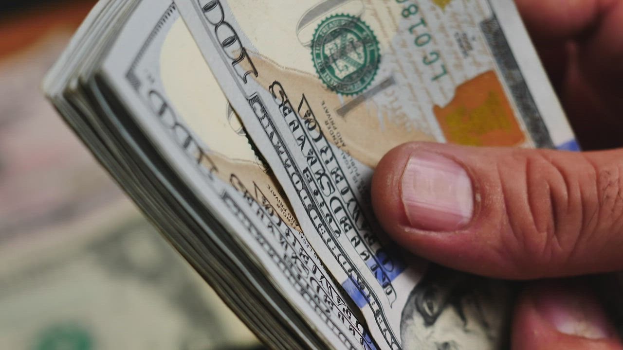 Close de mãos manuseando um maço de notas de cem dólares, simbolizando o resultado financeiro do alto engajamento de público.